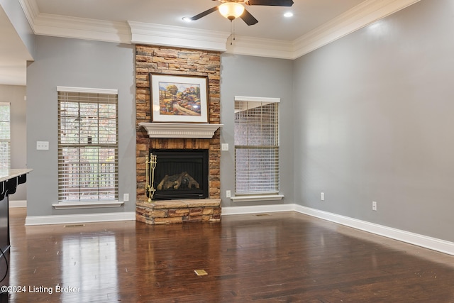 unfurnished living room featuring a stone fireplace, dark hardwood / wood-style flooring, ceiling fan, and crown molding