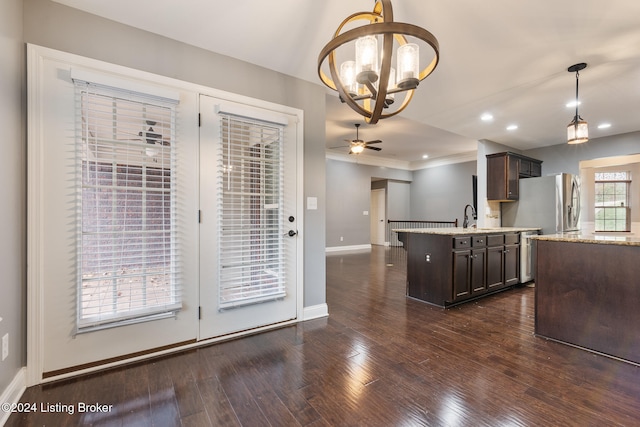 kitchen featuring stainless steel appliances, decorative light fixtures, dark brown cabinets, dark hardwood / wood-style flooring, and an island with sink