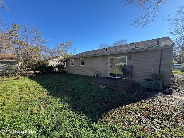 rear view of property with central AC unit and a lawn