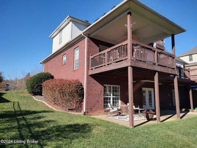 rear view of house featuring a lawn, a wooden deck, and a patio