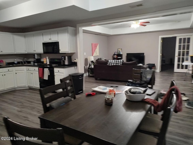 dining room featuring hardwood / wood-style floors, ceiling fan, and a tray ceiling