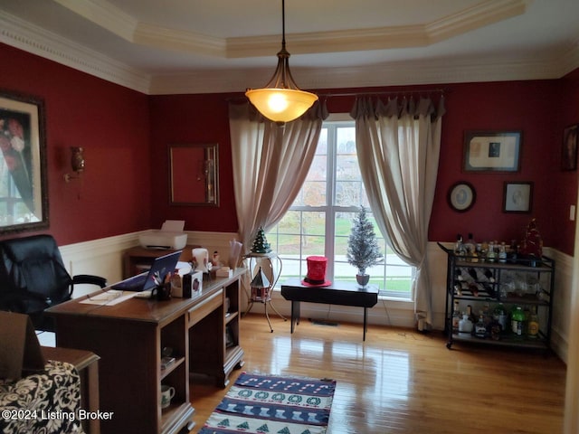 home office with wood-type flooring, a raised ceiling, and ornamental molding