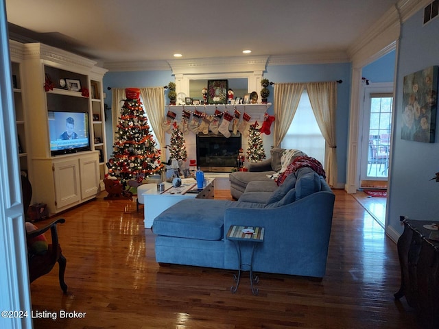 living room with a stone fireplace, dark wood-type flooring, and ornamental molding