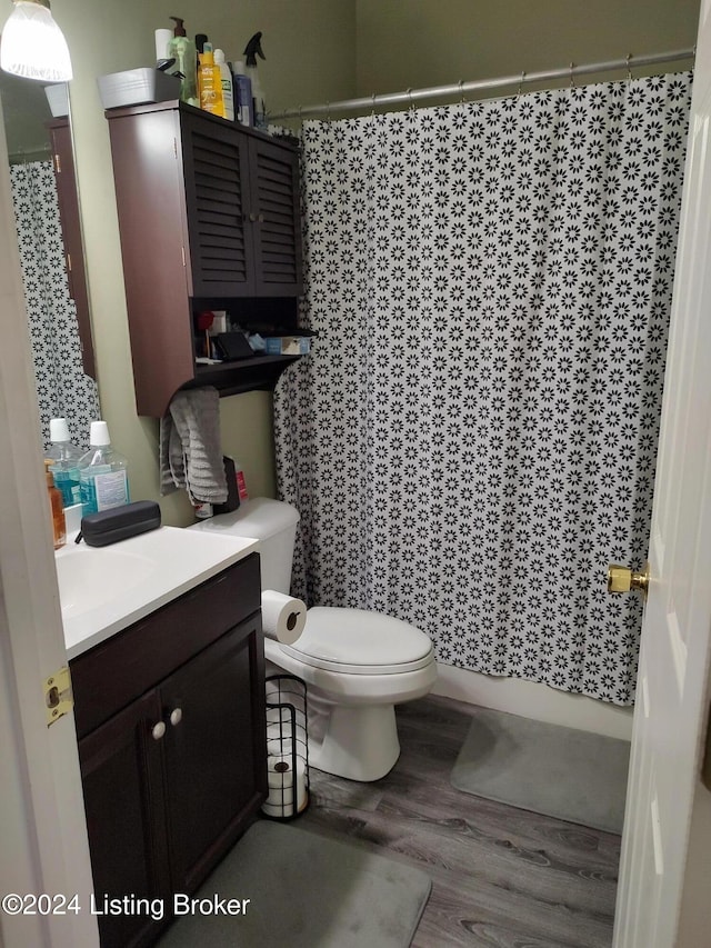 bathroom featuring hardwood / wood-style floors, vanity, curtained shower, and toilet