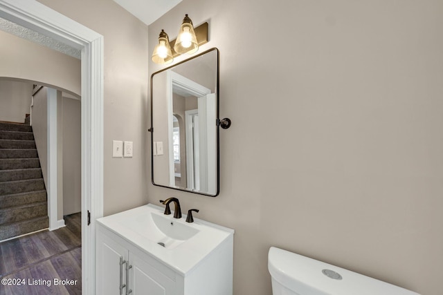 bathroom featuring wood-type flooring, toilet, and vanity