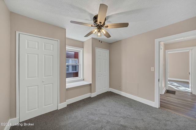 unfurnished bedroom featuring a textured ceiling, dark colored carpet, ceiling fan, and a closet