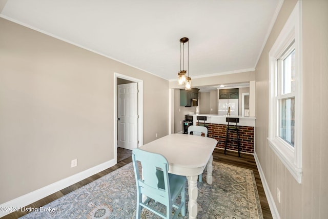 dining space with dark wood-type flooring and ornamental molding