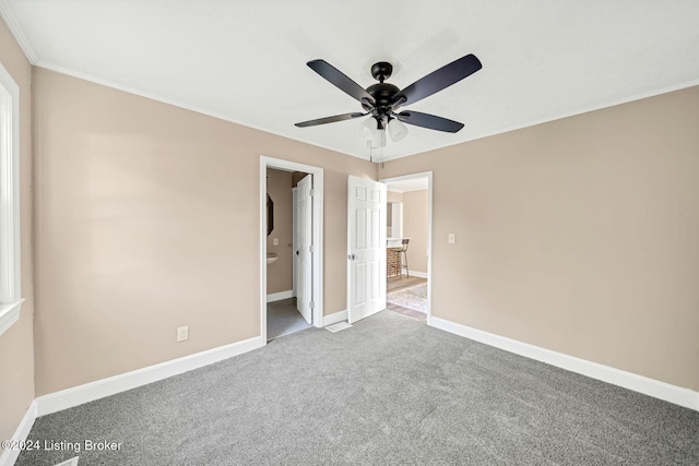 unfurnished bedroom featuring carpet flooring, ensuite bath, ceiling fan, and crown molding