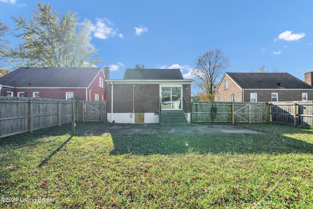 rear view of house with a lawn and a sunroom