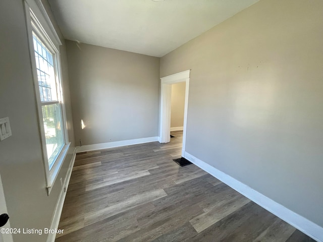 unfurnished room featuring vaulted ceiling and dark hardwood / wood-style flooring