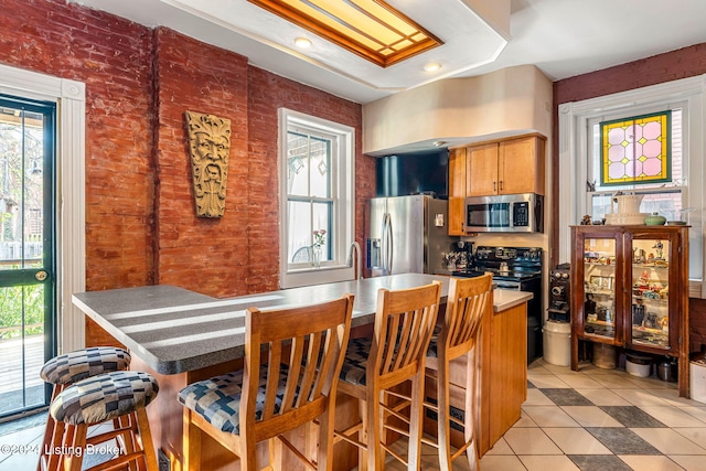 kitchen with appliances with stainless steel finishes, light tile patterned flooring, and a breakfast bar area