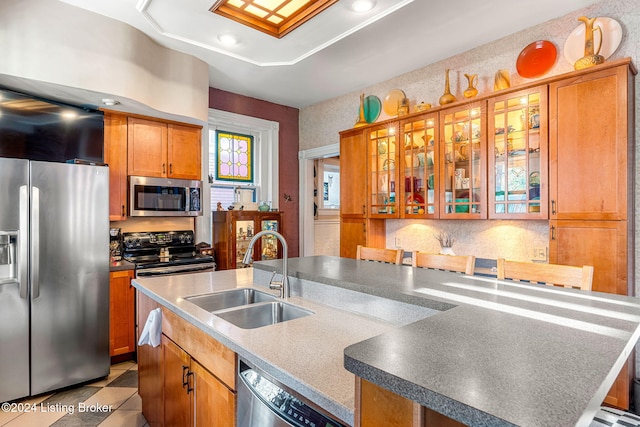 kitchen featuring light tile patterned floors, a center island with sink, sink, and appliances with stainless steel finishes