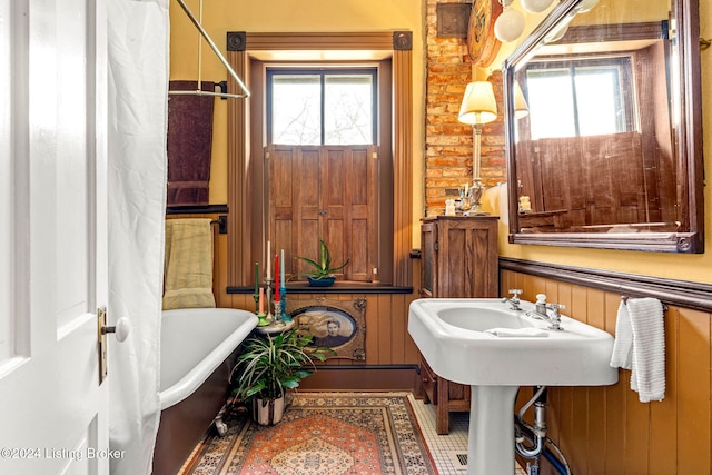 bathroom featuring a bathtub, wood walls, and brick wall