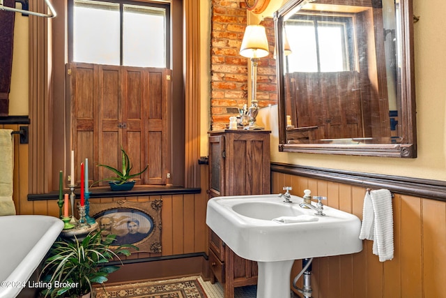 bathroom featuring wood walls and a tub