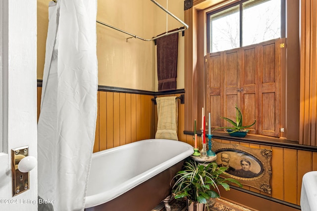 bathroom featuring wood walls and a tub