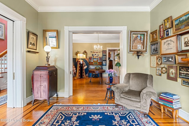 living area with wood-type flooring, a chandelier, and crown molding