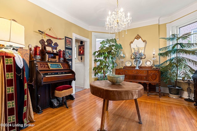 misc room featuring light wood-type flooring, a notable chandelier, a healthy amount of sunlight, and crown molding