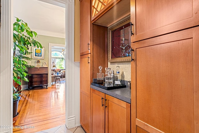 bar with backsplash, light tile patterned floors, and crown molding