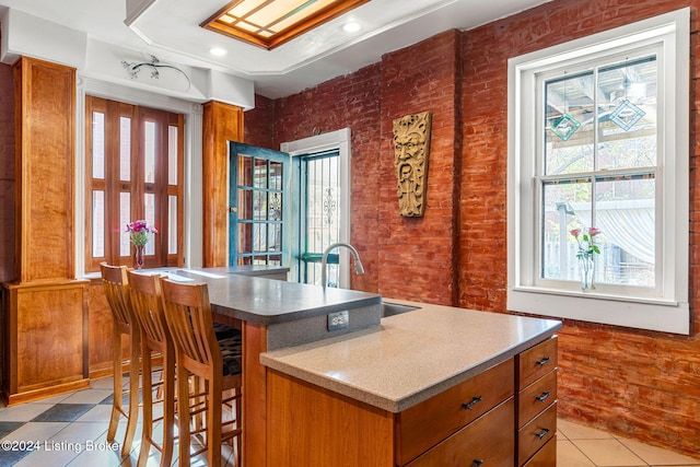 kitchen featuring light tile patterned floors, a center island, a breakfast bar, and sink