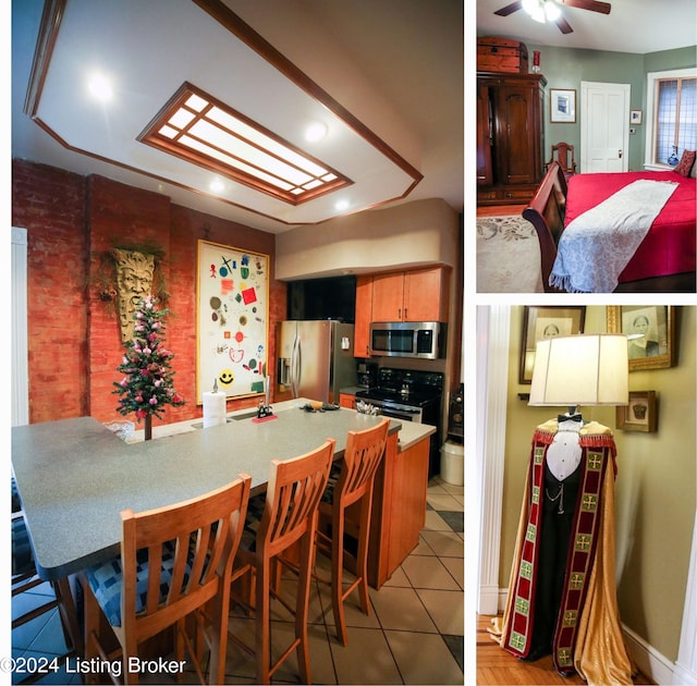 kitchen with kitchen peninsula, appliances with stainless steel finishes, a kitchen breakfast bar, ceiling fan, and light tile patterned floors