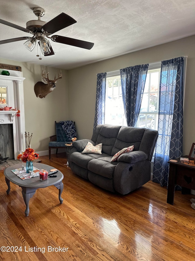 living room featuring wood-type flooring, a textured ceiling, and ceiling fan