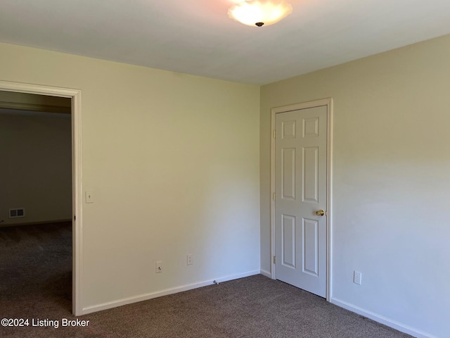 spare room featuring dark colored carpet