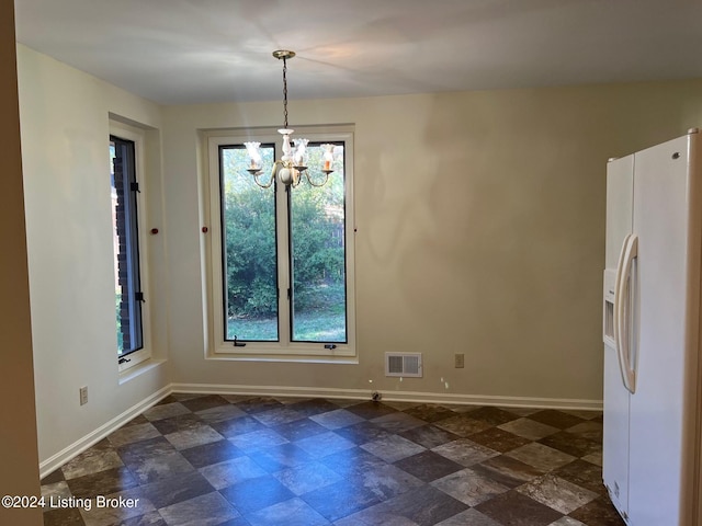 unfurnished dining area featuring an inviting chandelier and a healthy amount of sunlight