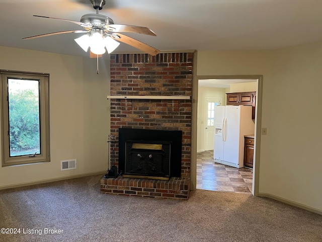 unfurnished living room featuring light colored carpet, ceiling fan, and a brick fireplace