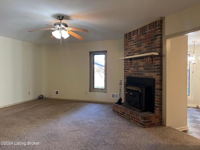 unfurnished living room with carpet, a wood stove, and ceiling fan with notable chandelier