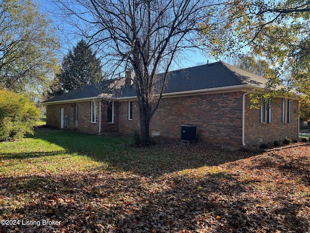 view of side of property featuring cooling unit and a yard