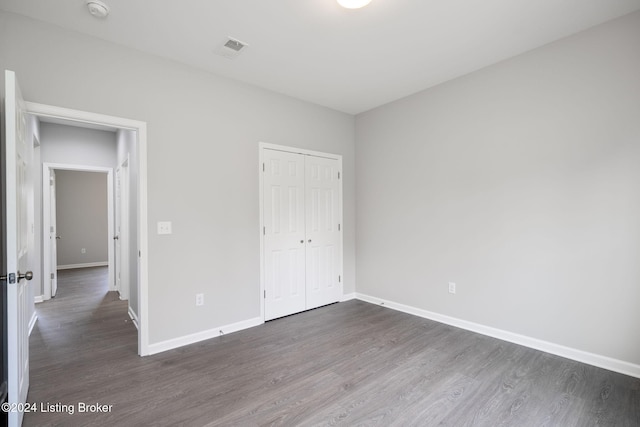 unfurnished bedroom featuring a closet and dark hardwood / wood-style floors