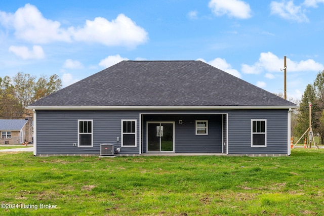 rear view of property with central AC and a yard