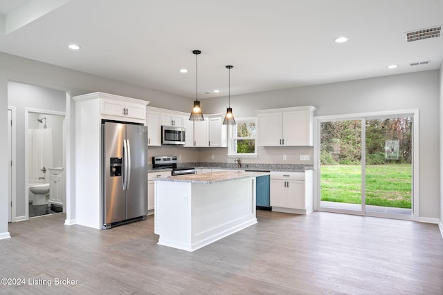 kitchen featuring light wood-type flooring, white cabinetry, appliances with stainless steel finishes, and hanging light fixtures