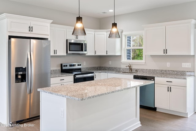 kitchen featuring sink, appliances with stainless steel finishes, light hardwood / wood-style flooring, a center island, and white cabinets