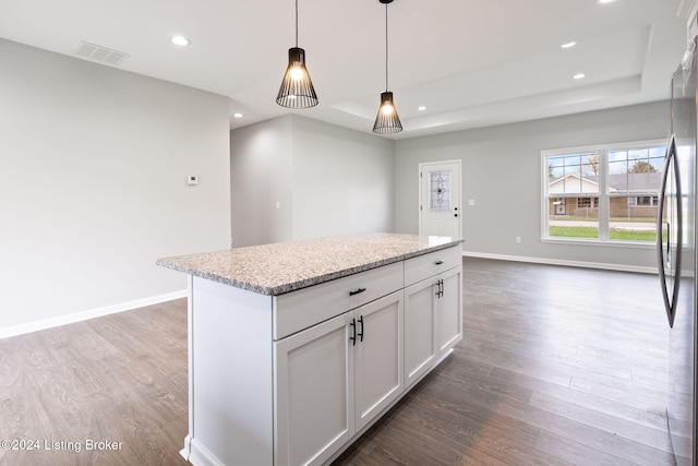 kitchen with wood-type flooring, a kitchen island, stainless steel refrigerator, pendant lighting, and white cabinets