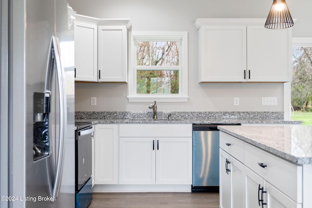 kitchen with white cabinetry, hardwood / wood-style floors, appliances with stainless steel finishes, and light stone countertops