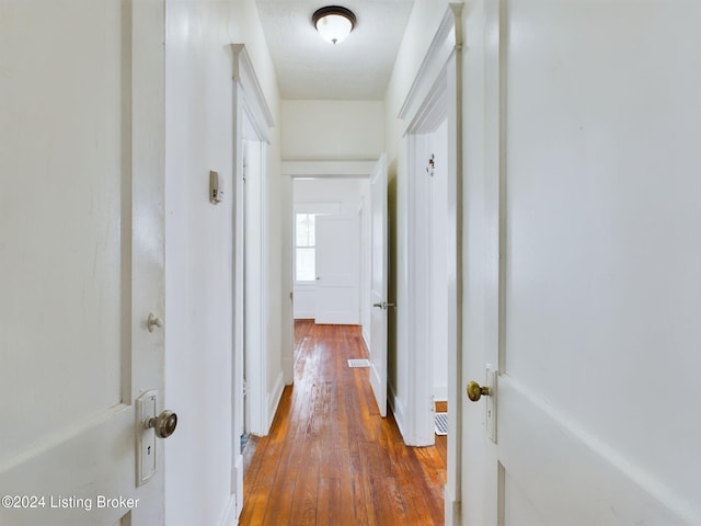 hall featuring a textured ceiling and hardwood / wood-style flooring