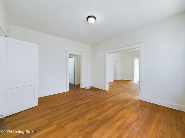 spare room featuring hardwood / wood-style flooring and a textured ceiling