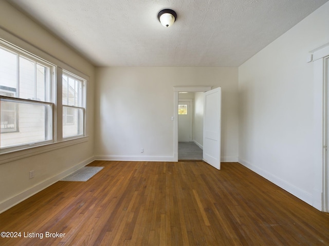 unfurnished room with a textured ceiling and dark wood-type flooring