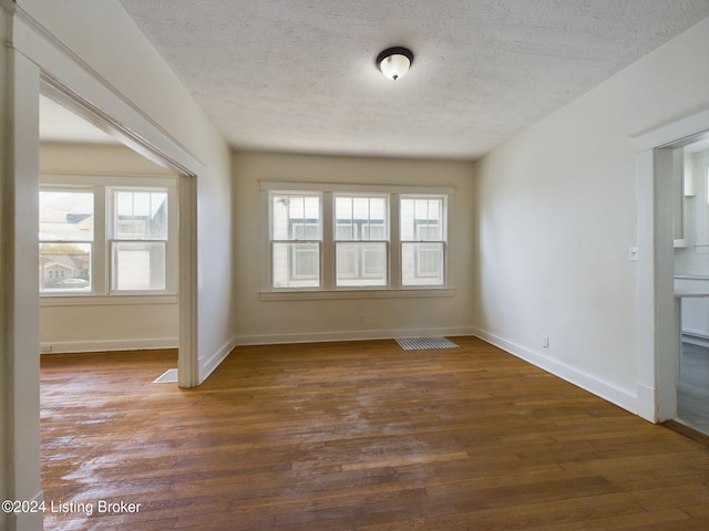 unfurnished room featuring a textured ceiling, dark hardwood / wood-style flooring, and plenty of natural light