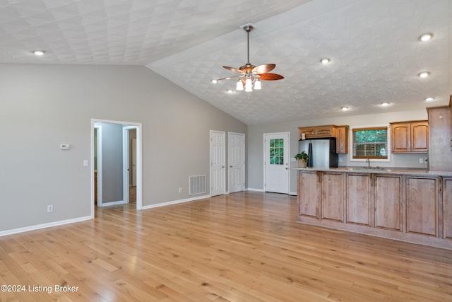 kitchen with sink, ceiling fan, high vaulted ceiling, light hardwood / wood-style flooring, and stainless steel fridge