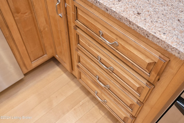 interior details with light stone countertops and light wood-type flooring