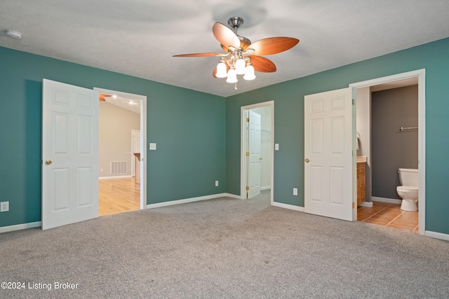 unfurnished bedroom featuring ensuite bathroom, ceiling fan, a spacious closet, and light colored carpet