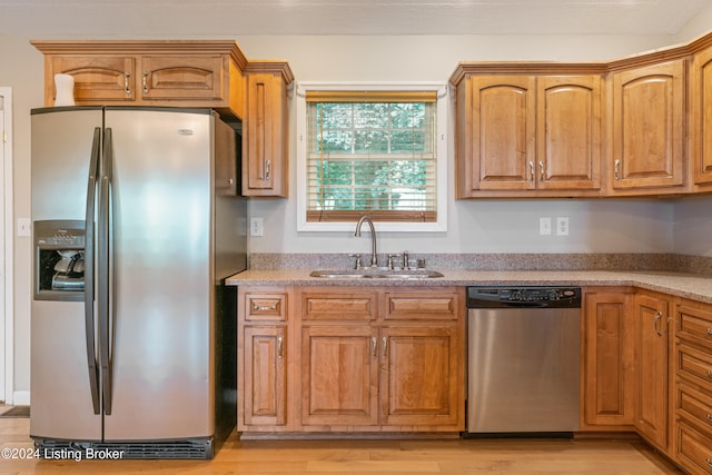 kitchen with stainless steel appliances, sink, and light hardwood / wood-style flooring