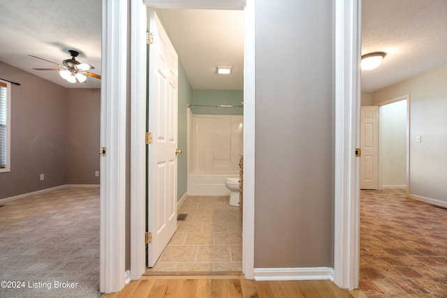 hall featuring a textured ceiling and light carpet