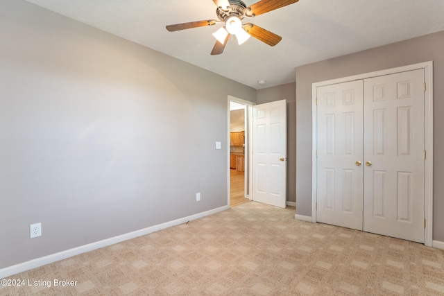 unfurnished bedroom featuring light carpet, ceiling fan, and a closet