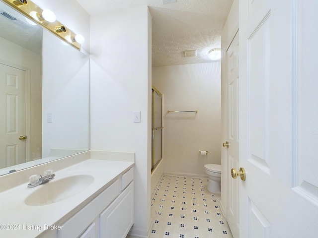 bathroom featuring vanity, a textured ceiling, toilet, and a shower with door