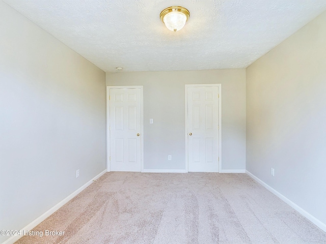 unfurnished bedroom with a textured ceiling and light colored carpet