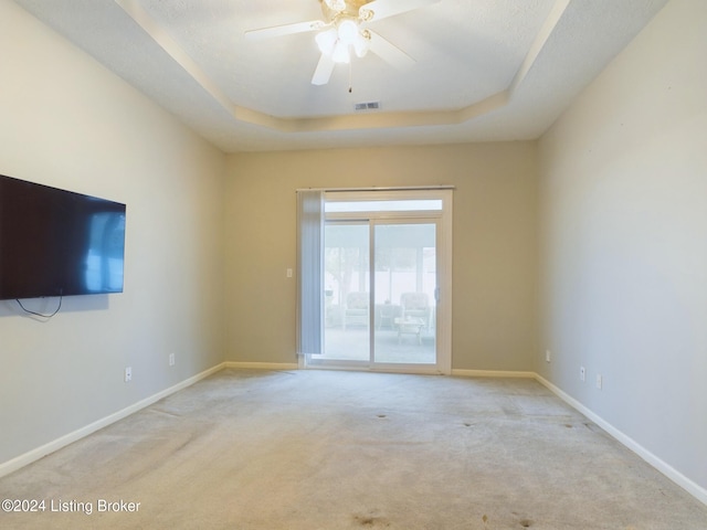 unfurnished room with light carpet, a raised ceiling, and ceiling fan