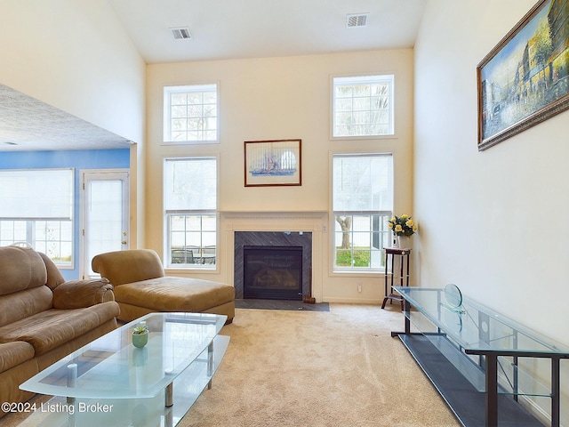 carpeted living room with a high end fireplace, a towering ceiling, and plenty of natural light